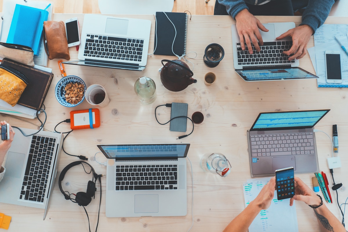Equipe colaborando em uma mesa com notebooks durante o desenvolvimento de um produto digital.